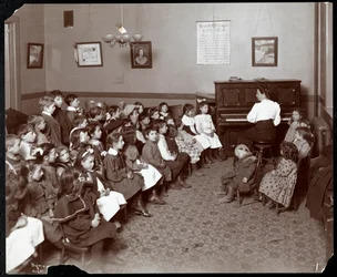 Women and children in a room with flowers at the National Fruit and Flower Guild, 247 Spring Street, New York, 1906